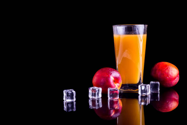 A glass of peach juice isolated on black background, copy space.