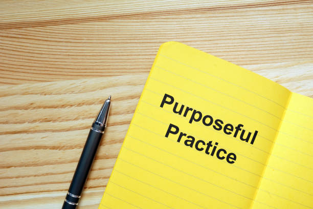 istock Writing note showing Purposeful Practice. The text is written on a paper of yellow notebook. Conceptual photo shows colored papers, pen, colored background. 1166999098