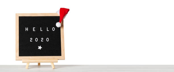 istock Christmas or new year frame or mockup for your project. Hello 2020 words on a letter board with santa hat against white isolated background 1166999185