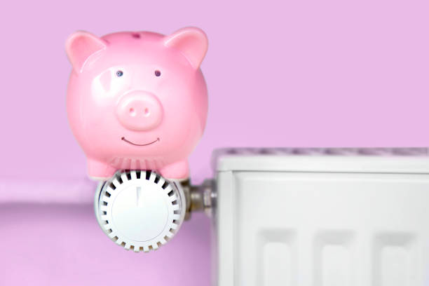 Piggy bank sitting on the heater Piggy bank sitting on the heater / thermostat temperatur stock pictures, royalty-free photos & images