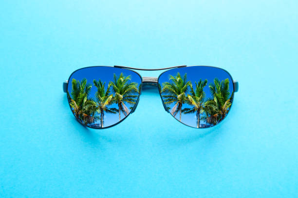 istock Summer vacation concept. Sunglasses with palms and blue sky on blue background. 1167003529