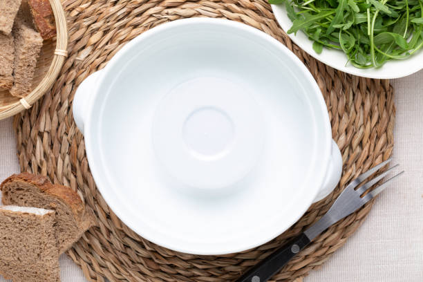 istock Empty white pot. On delicate beige tablecloth. Includes bread and green arugula. Concept to include your food and your text. 1167015477