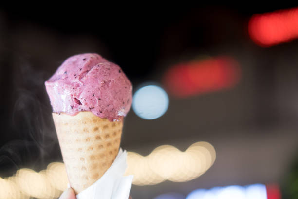 istock Blueberry ice cream in waffle cone on young man hand with light night background 1167017695