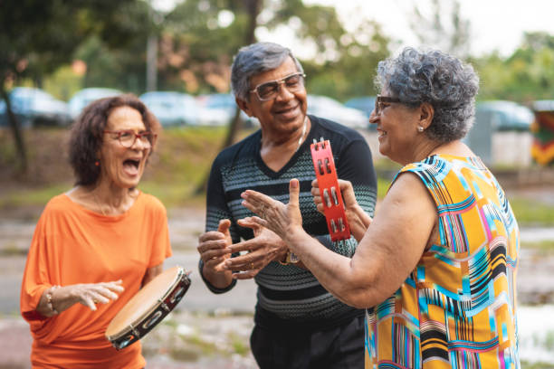 senioren spielen tamburin, singen und tanzen im öffentlichen park - traditional song stock-fotos und bilder