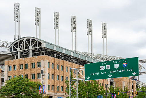Facade of Progressive Field in downtown Cleveland, Ohio with street signs providing visitors with directions. It’s home to the MLB Cleveland Indians.