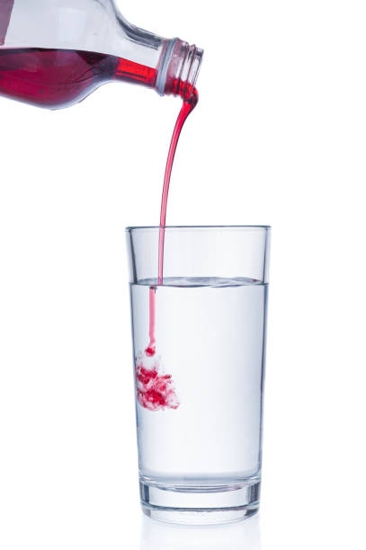 istock Cranberry and black currant syrup pouring into water glass on white background 1167022335