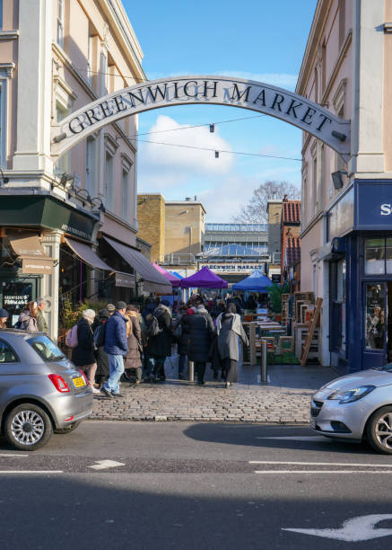 People visiting Greenwich Market (World Heritage Site) on sunny Saturday morning, walking to stalls from the street, passing under large sign. London, United Kingdom - February 02, 2019: People visiting Greenwich Market (World Heritage Site) on sunny Saturday morning, walking to stalls from the street, passing under large sign. greenwich london stock pictures, royalty-free photos & images