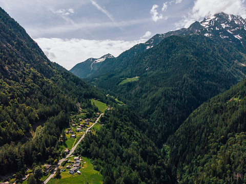 Aerial view of picturesque valley in area of wild green Swiss hills. Bird's eye view of breathtaking countryside in mountains. Beautiful small town surrounded by stunning nature landscape