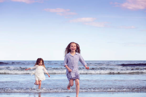 Lifestyle photo of two little sisters having fun playing on a beach in Kennebunkport, Maine in the summer.