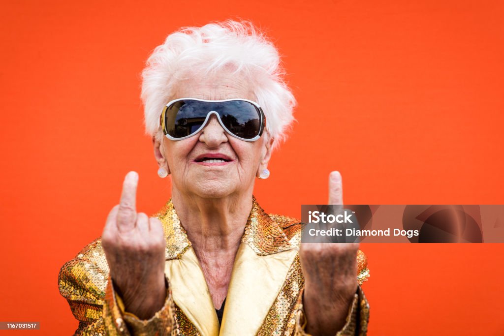 Eccentric senior woman portrait Funny and extravagant senior woman posing on colored background - Youthful old woman in the sixties having fun and partying Senior Women Stock Photo