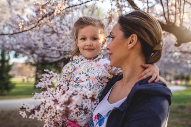 istock Beautiful child being held by her young mother under a blossoming tree 1167034624