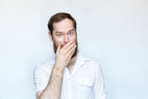 istock Smiling man covering his mouth with hand over gray background 1167036252