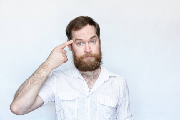 istock Bearded man pointing finger at his head over gray background 1167036391