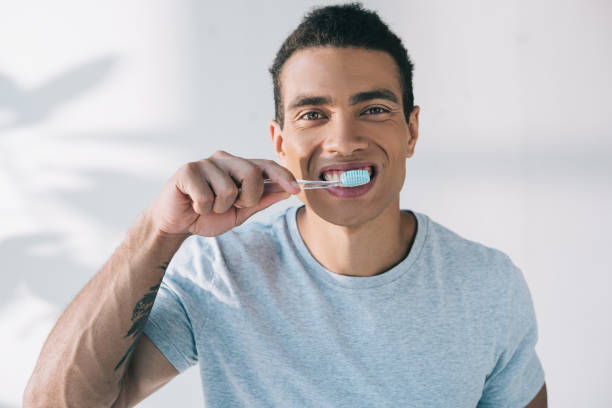 istock young man brushing teeth with toothbrush and looking at camera 1167036540