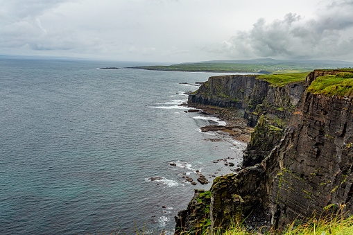 Landscape of the rocky cliffs in the Irish countryside along the coastal walk route from Doolin to the Cliffs of Moher, geosites and geopark, Wild Atlantic Way, rainy day in county Clare in Ireland