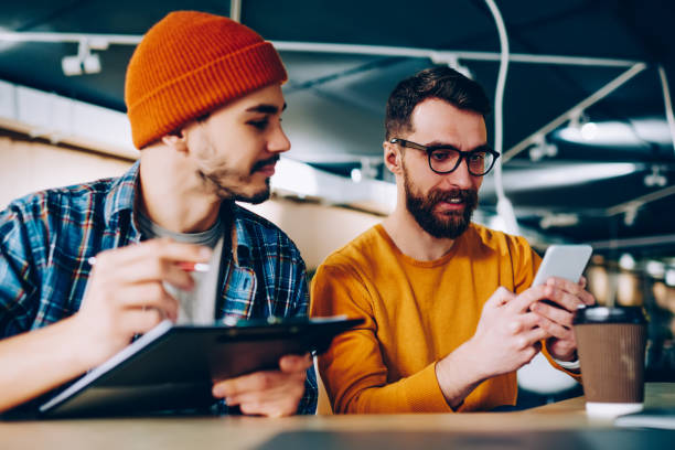 istock Millennial hipster guys dressed in casual apparel using 4g connection for searching information on internet browser, caucasian male friends reading news in social networks while sitting indoors 1167037728