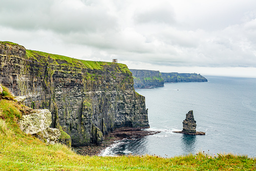 Lateral view of the Cliffs of Moher and the Branaunmore sea stack, geosites and geopark, Wild Atlantic Way, wonderful cloudy spring day in County Clare in Ireland