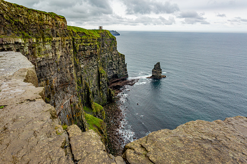 Cliffs of Moher and the Branaunmore sea stack seen from a plateau, geosites and geopark, Wild Atlantic Way, wonderful spring cloudy day in County Clare in Ireland