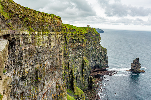Beautiful view of a vertical wall of the Cliffs of Moher and the Branaunmore sea stack, geosites and geopark, Wild Atlantic Way, wonderful cloudy spring day in County Clare in Ireland