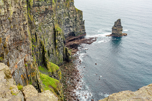 View of a small part of the coast of the Cliffs of Moher and the Branaunmore sea stack, geosites and geopark, Wild Atlantic Way, wonderful cloudy spring day in county Clare in Ireland