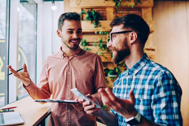 istock Successful male startuppers discussing plan together for work smiling and gesturing, happy hipster guys having friendly conversation about business information having meeting in coworking office 1167038130