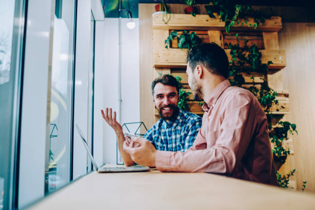 istock Cheerful bearded male student laughing and gesturing during conversation with friend in campus looking at camera, positive hipster guy happy about prosperous online project talking with colleague 1167038270