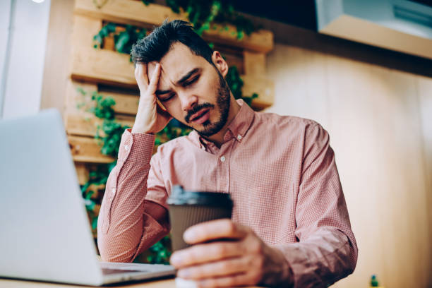 istock Tired sad male student with closed eyes upset with education problems preparing for exams, exhausted hipster guy overworked in coworking space sitting with coffee for completing before deadline 1167038377