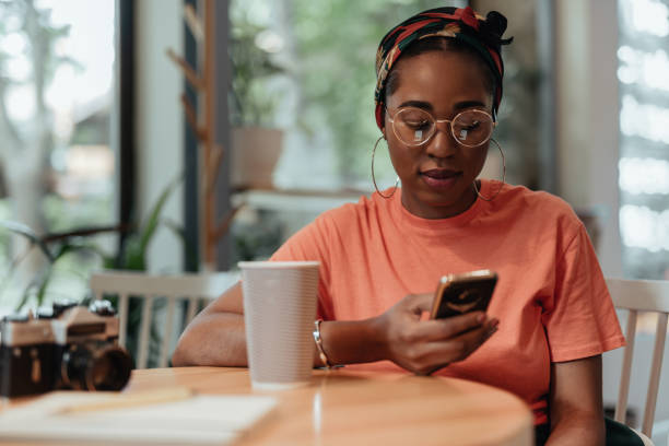 istock Young afro-american woman using smartphone in cafe 1167038488
