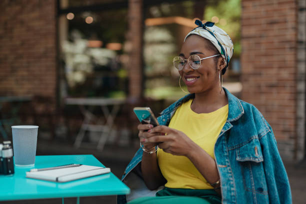 fêmea de sorriso do americano africano com smartphone ao ar livre - places to go - fotografias e filmes do acervo