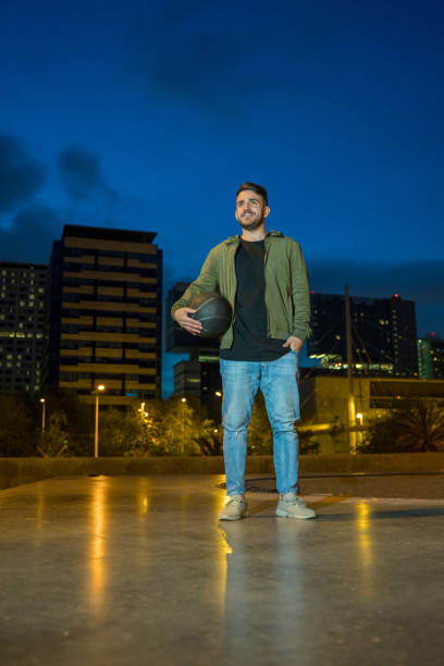 istock Man holding a basket ball with Barcelona skyline background. 1167038648