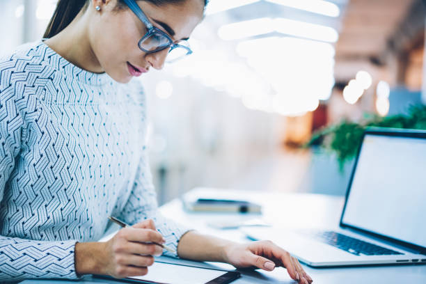 istock Pensive female designer making drawing via modern touchpad connected wih laptop computer,professional administrative manager of clinic using stylus for signing electronic documents in database 1167039921