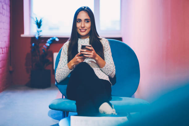 istock Positive brunette woman using mobile phone for networking on work break in office,young hipster girl chatting with friend online on smartphone share multimedia files sitting at share indoors 1167040604
