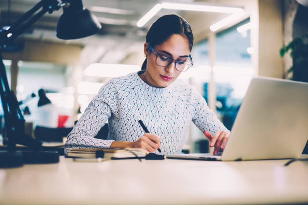 istock Concentrated woman in eyewear working on project making accountings and analyzing information via laptop computer,female student preparing for exams in college library using netbook sitting at desktop 1167040646