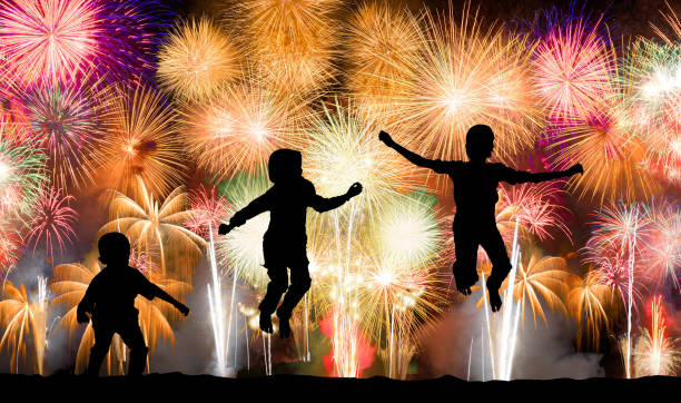 istock Silhouette of kids jumping over colorful firework 1167040689