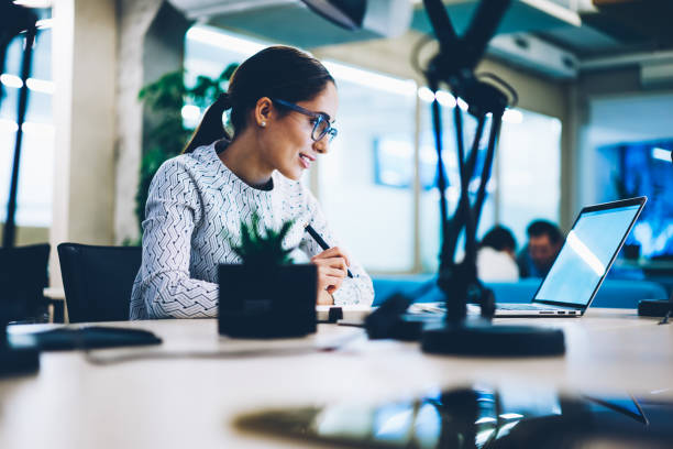 istock Skilled female office manager in eyewear analyzing information about business reading from netbook sitting at desktop,concentrated secretary checking mail via laptop computer organizing work 1167040736