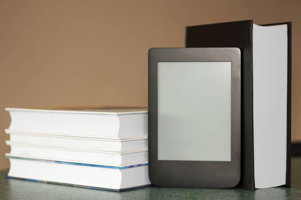istock Modern e-book on the background of a stack of thick paper books. Close-up with selective focus. Training and technology concept 1167041270
