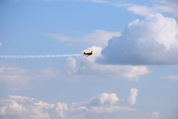 istock A yellow passenger plane flying through the sky full of puffy clouds in a dynamic manner while generating some smoke behind it seen on a summer sunny day in Poland during a hike 1167046481