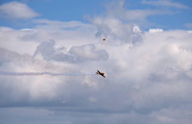 istock Two yellow passenger planes flying dynamically at a high altitude with one of them generating some white smoke behind it and the second one being angled in the distance seen on a summer day away 1167046508