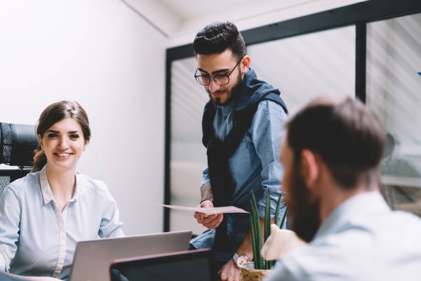 istock Group of young people dressed in formal wear collaborating on developing business project during brainstorming in modern office.Team of male and female employees discussing strategy of cooperation 1167050428