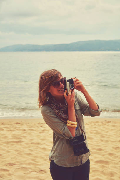 istock Attractive woman holding camera on the tropical beach. 1167054514
