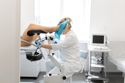 Un ginecólogo examina a un paciente en una silla ginecológica. Flujo de trabajo de un ginecólogo photo
