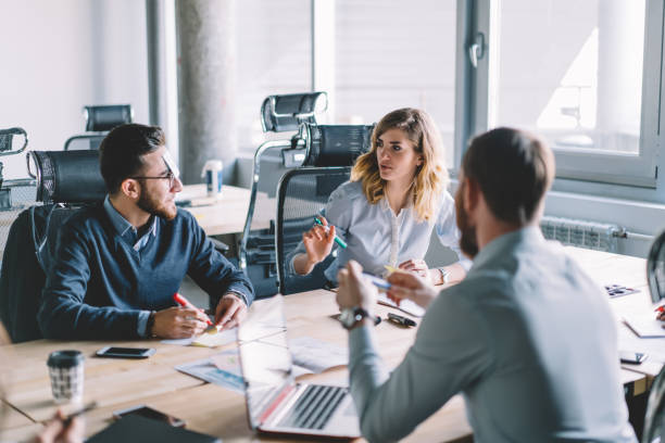 istock Young people in formal wear playing game using colorful stickers during interesting brainstorming in modern office interior.male and female colleagues writing information on paper notes 1167058015