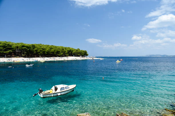 Primosten, Croatia - July 29, 2019: People on beautiful beach. Nice, warm, summer day, with blue sky and ocean.