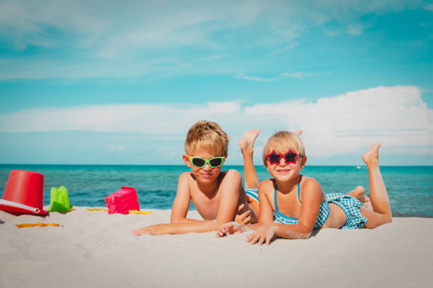 istock cute boy and girl play with sand on beach 1167070085