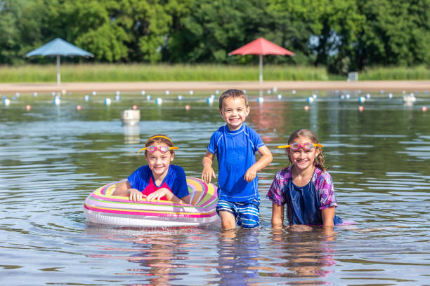 três crianças que nadam na praia no dia de verão - inner tube swimming lake water - fotografias e filmes do acervo