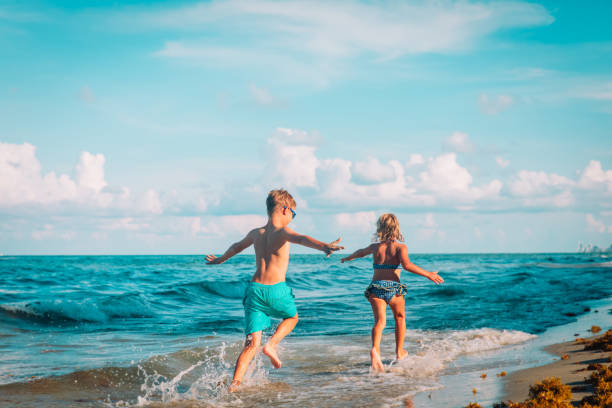 istock happy boy and girl run play at beach 1167073837