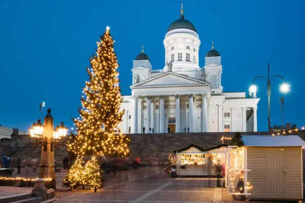 Photo of Helsinki, Finland. Christmas Xmas Holiday Carousel On Senate Square Near Famous Landmark. Lutheran Cathedral At Winter Evening