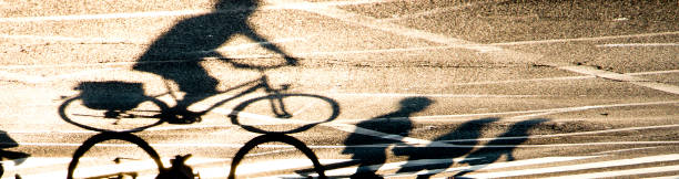 silueta de sombra borrosa de una persona montando en bicicleta y peatones cruzando la calle con marcas de carretera - rules of the road fotografías e imágenes de stock