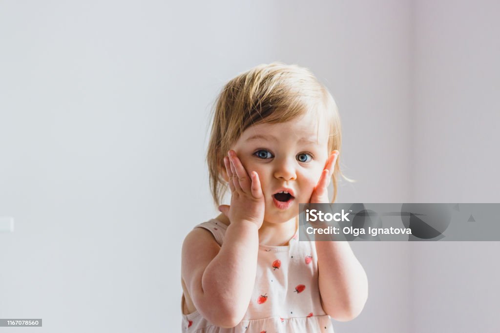 Surprised shocked child toddler girl with hands on her cheeks isolated on light background Baby - Human Age Stock Photo