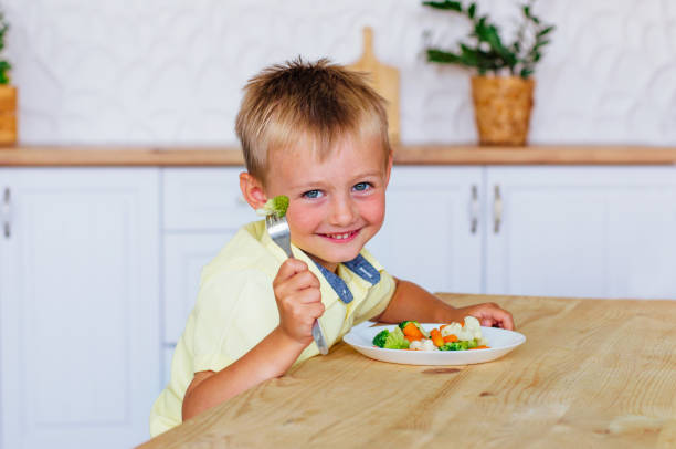 istock Smiling little boy eating mixed vegetables salad in the kitchen 1167082885